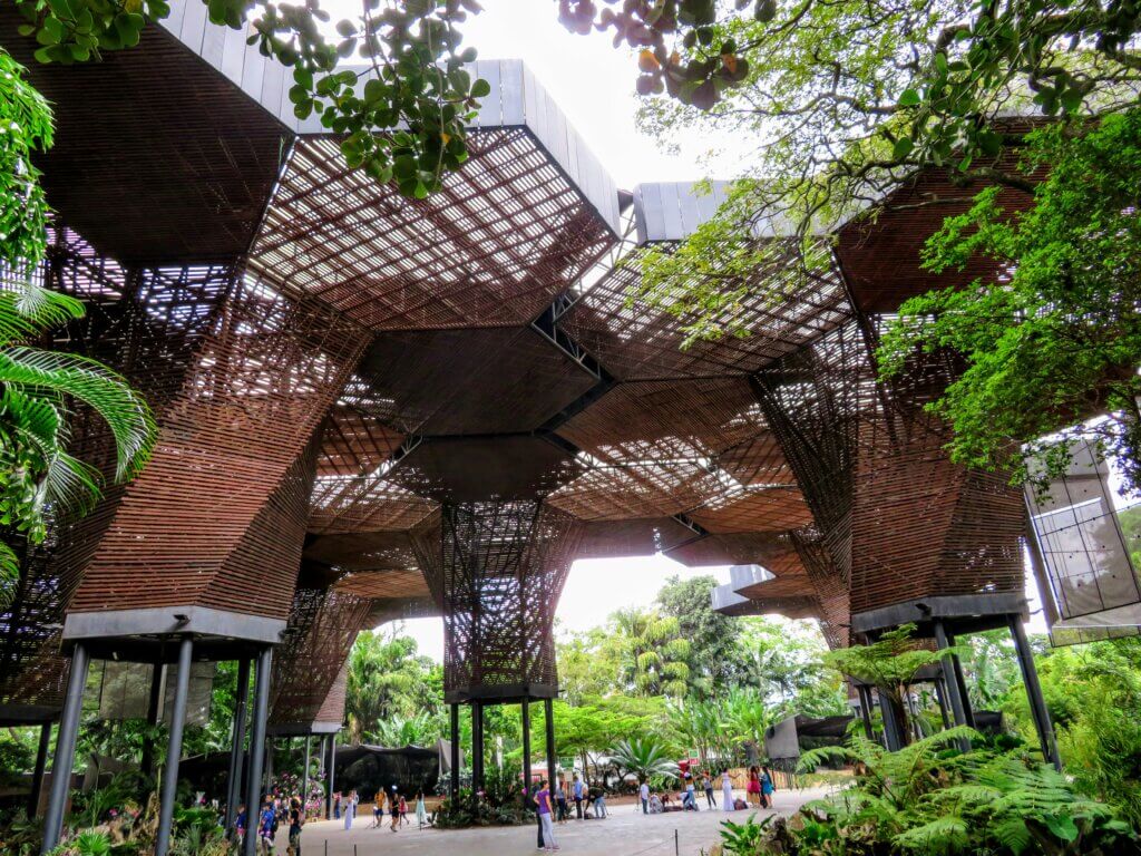 Modern eco-friendly urban park with lush greenery and innovative wooden canopy structures in Medellin, Colombia.