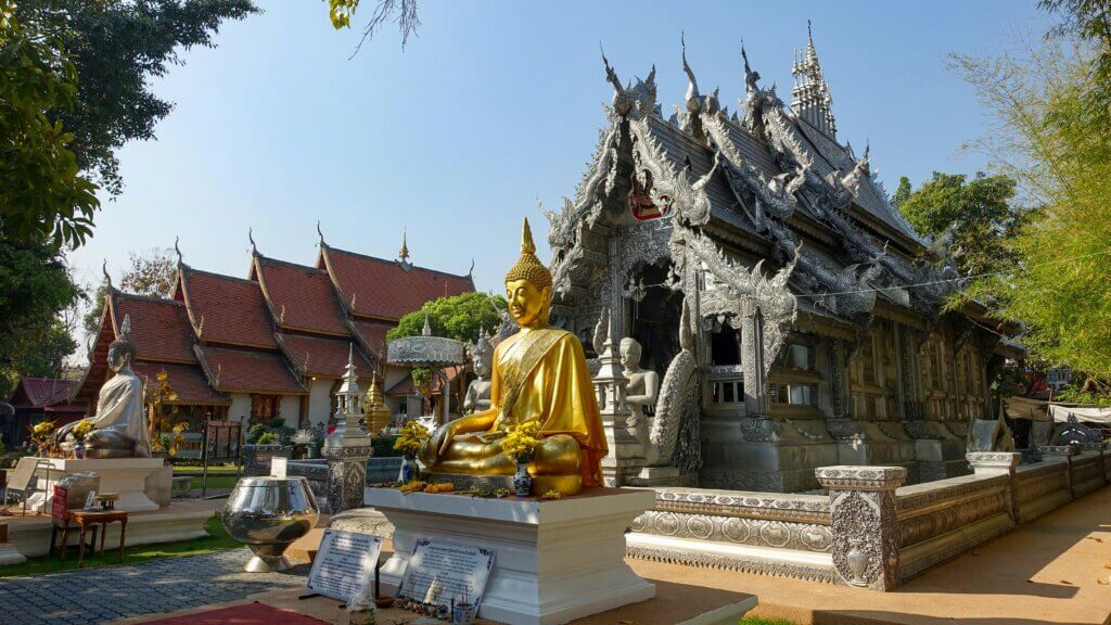 Traditional Thai temple with golden Buddha statues and intricate architecture in Chiang Mai, Thailand.