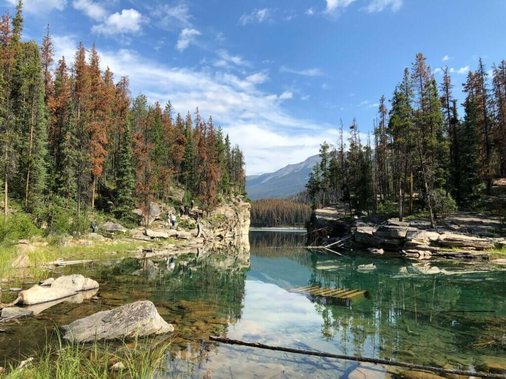 Crystal-clear alpine lake reflecting snow-capped mountains in Jasper National Park, Canada.