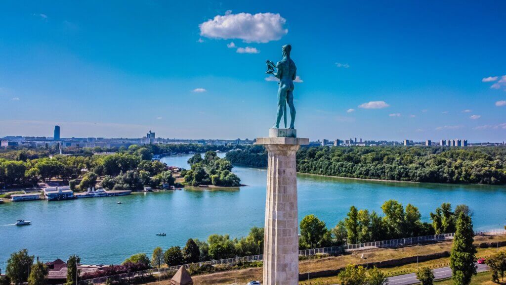 A panoramic view from Kalemegdan Fortress in Belgrade, Serbia, featuring the iconic Pobednik monument and the confluence of the Sava and Danube rivers.