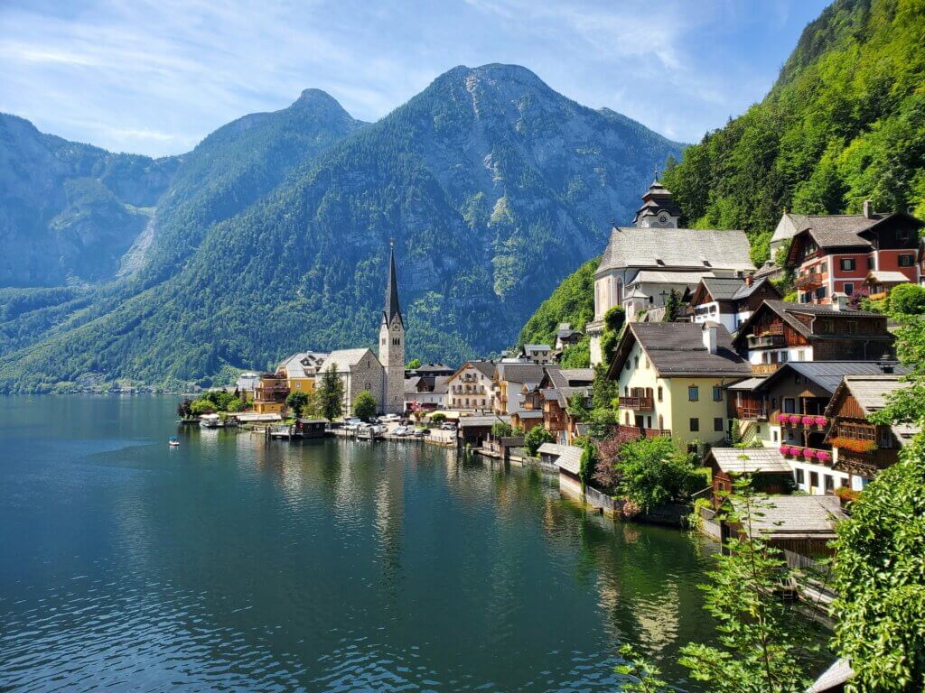 Picturesque Hallstatt village in Austria with wooden chalets on steep slopes reflected in Hallstätter See with Dachstein mountains behind