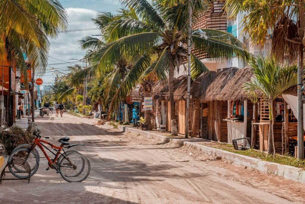 Sandy streets and palm trees on Isla Holbox, Mexico with bicycles and rustic houses